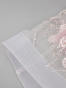 Close-up of a floral embroidered fabric with beads on a gray background