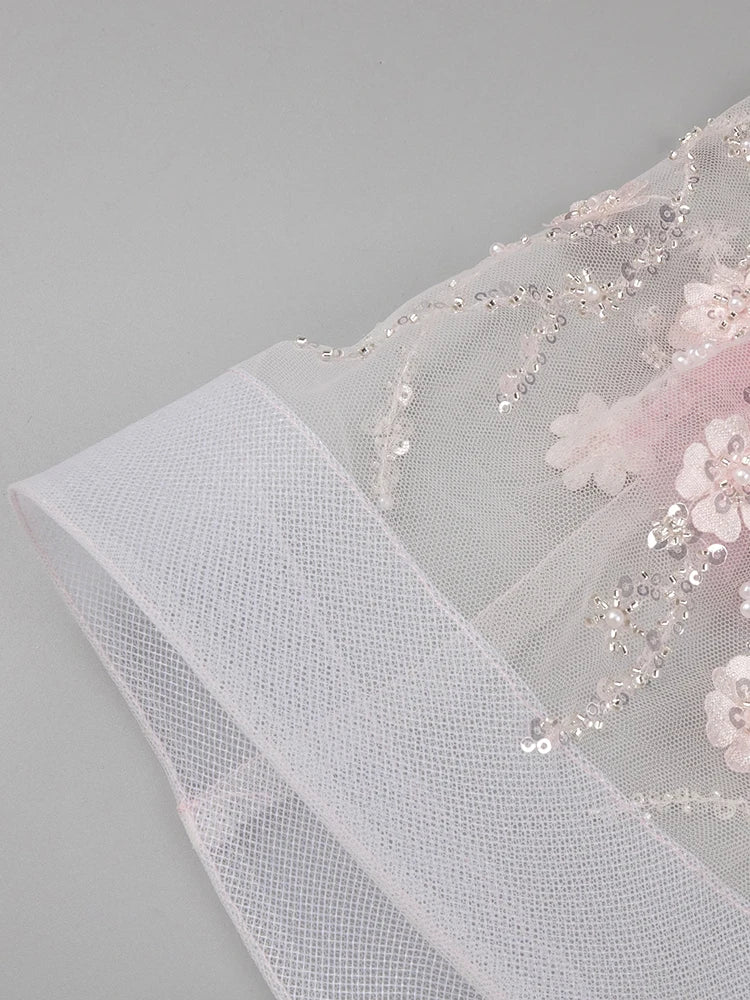 Close-up of a floral embroidered fabric with beads on a gray background