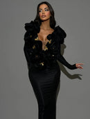 Woman wearing a black dress with gold buttons against a gray background